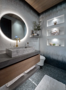 Floating vanity and ombre tiles with round backlit mirror and wall niches in this powder bath design