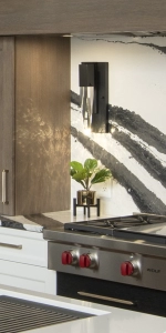 Close up detail of a wall sconce on quartz backsplash in new home kitchen, with custom cabinetry from Edmond Kitchen and Bath in OKC