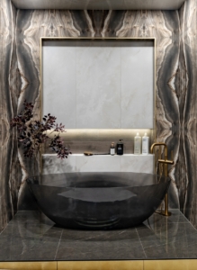 Smoked acrylic bathtub surrounded by book matched stone in this luxury bathroom design