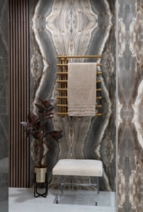 Heated towel warmer in gold placed on the book matched tiles in this shower design