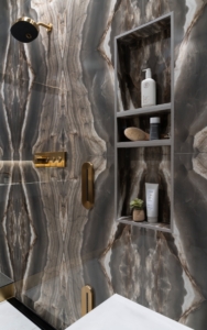 Bottle niche designed into the book matched stone tiles in this shower renovation with Kohler shower valve