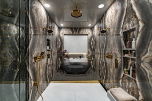 Book matched stone walls with wetroom shower and acrylic tub in this bath design