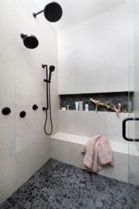 White porcelain tiled shower with black fixtures and infinity niche in this remodeled shower