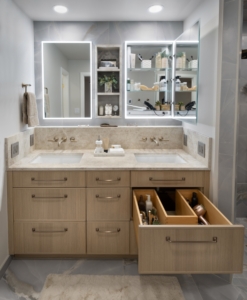 Custom cut vanity drawers to wrap plumbing. Lit medicine cabinetry for additional storage.