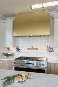 Brass vent hood flanked by our custom cabinetry
