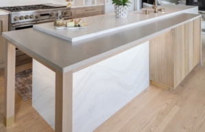 Cantilevered countertop on luxury island in this renovated kitchen with custom reeded-door cabinetry
