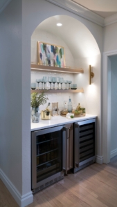 Arched top beverage area with custom cabinetry and floating shelves