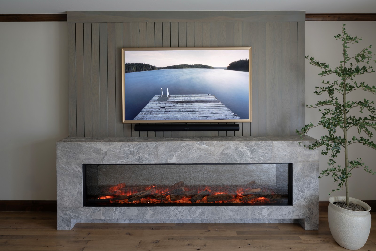 Custom 11 foot long electric fireplace design created and built for this Master Bedroom remodel. Frame TV on top showing a lake scene.