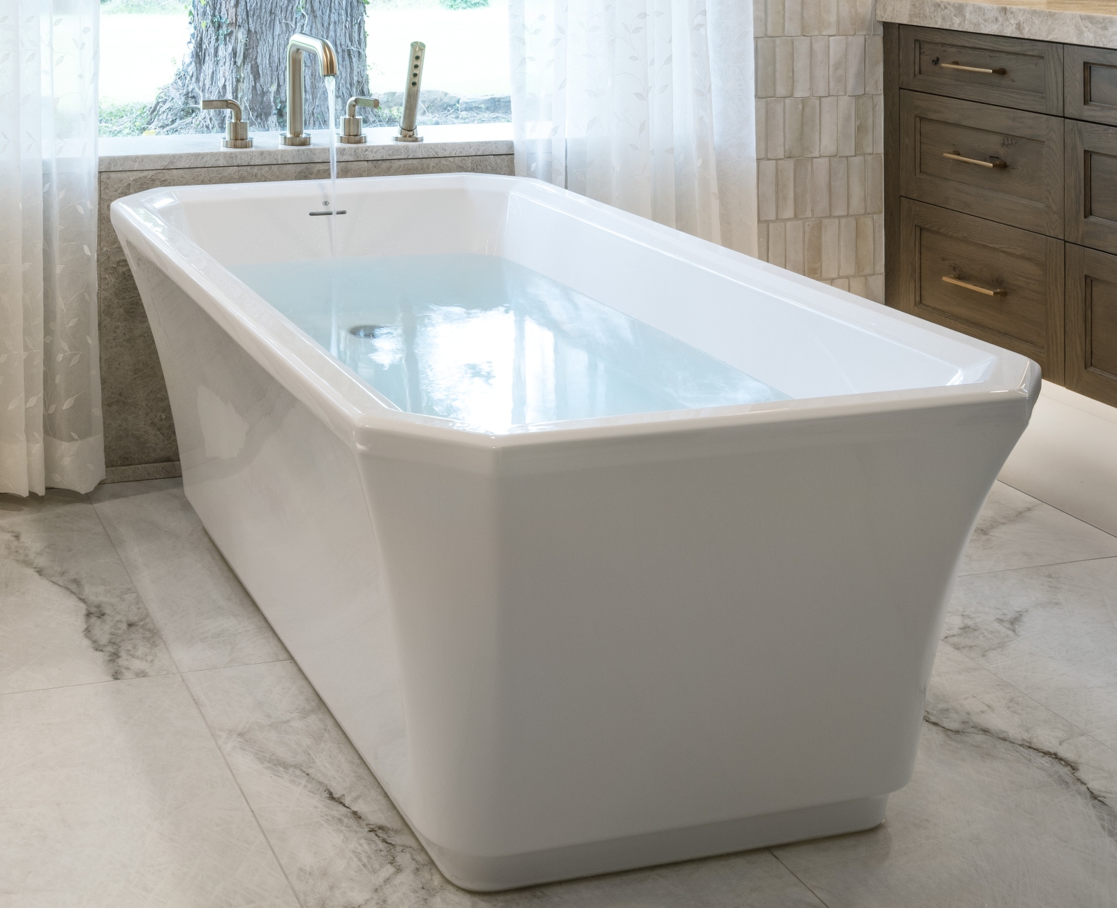 Edmond-bathroom-remodel-freestanding-bathtub Bathtub beneath a large window with quartz plumbing ledge and removable service-access panels