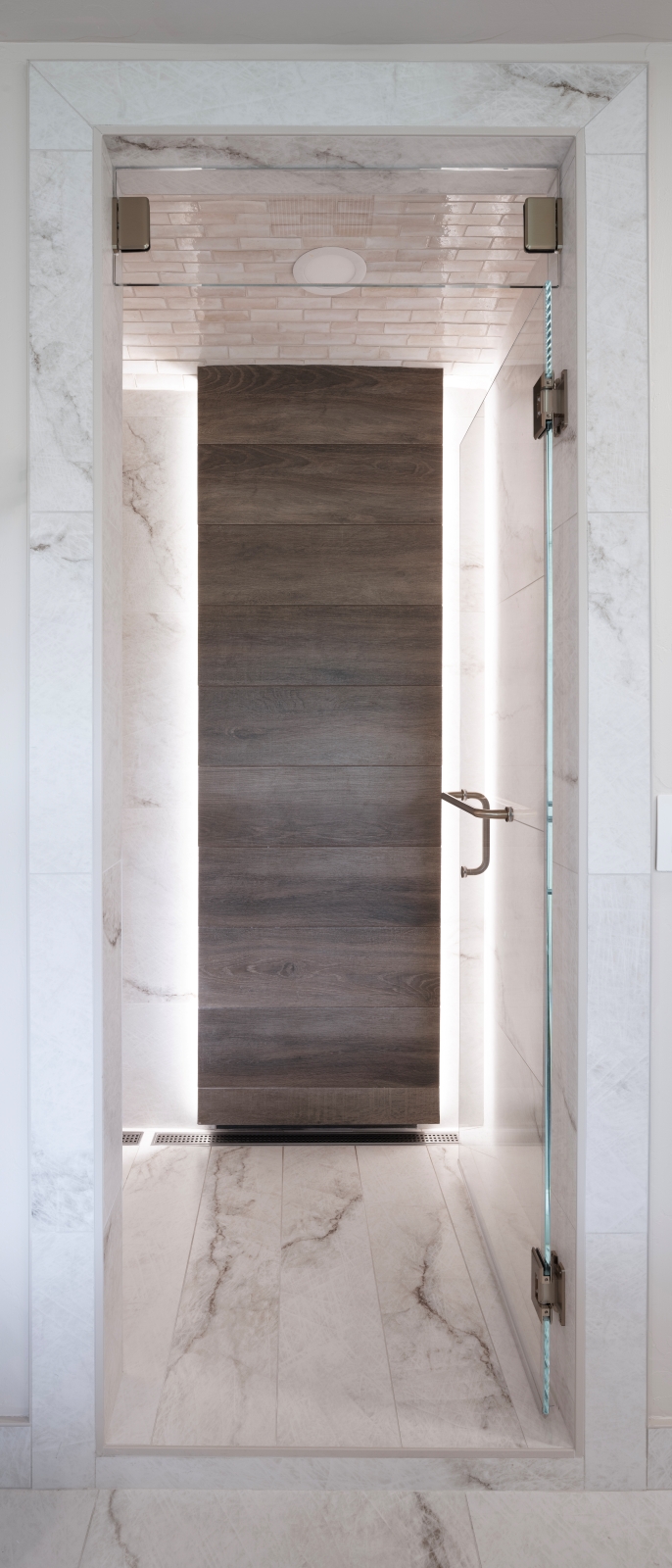 Edmond-master-shower-custom-tilework-accent-wall Edge-lit wood-look tile shower feature wall with matching built-in bench